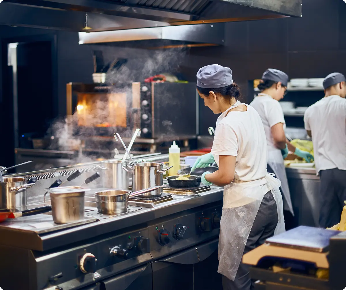 Chefs working at a commercial range under an extraction hood